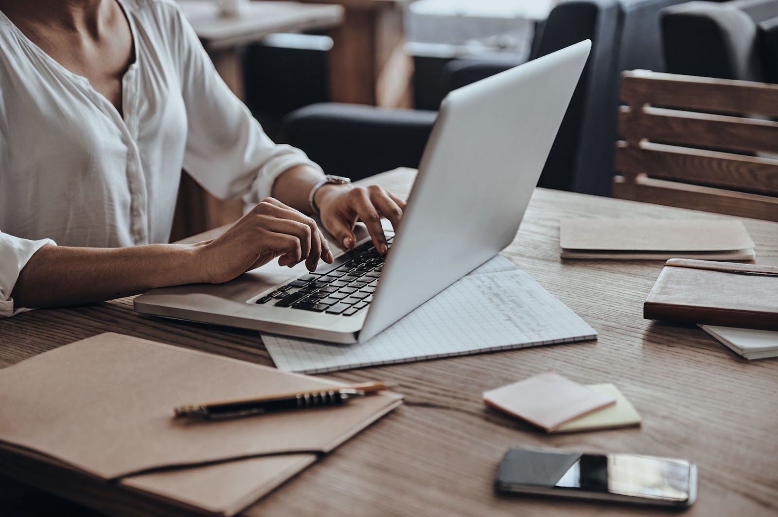 Čo všetko potrebujete na prepis? | WebJET CMS Žena pracujúca na notebooku, obkolesená zápisníkmi a papiermi s poznámkami.